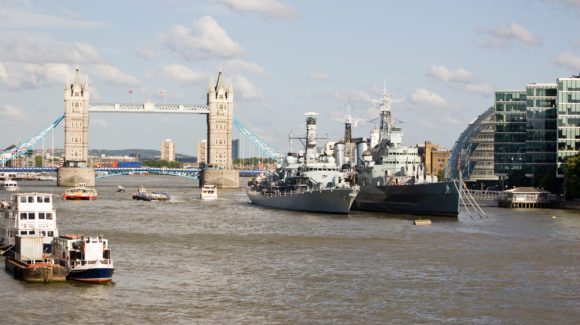 View of the River Thames from London Bridge, City of London. Tower Bridge in the background with the naval ships HMS Portland and HMS Belfast moored towards the centre.